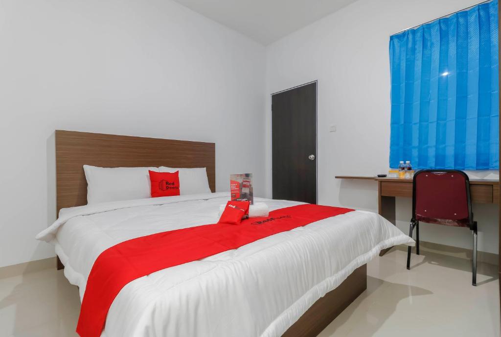 um quarto com uma cama grande e um cobertor vermelho em RedDoorz Plus near Kepri Mall em Batam Center
