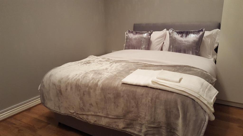 uma cama com um cobertor branco e almofadas em Haus Serviced Living em Braintree