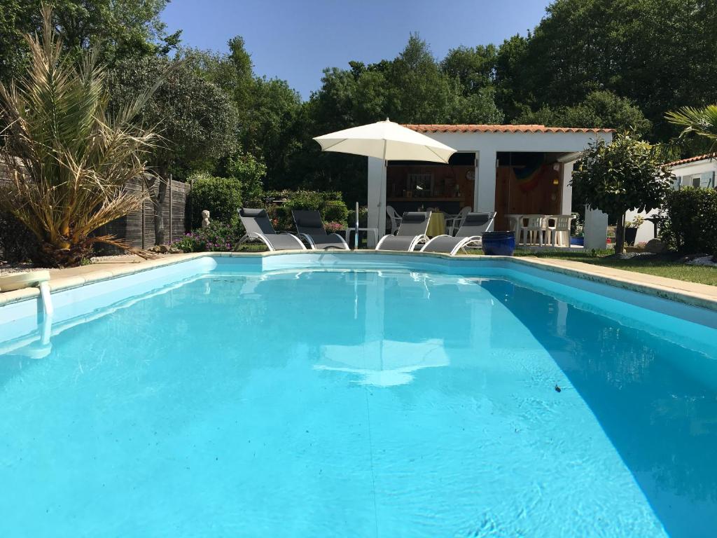 a large blue swimming pool with chairs and an umbrella at La Ferme du Preneau in Challans