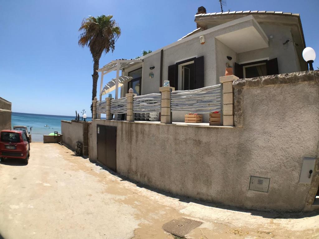 uma casa na praia com uma palmeira em Appartamento sul mare em Noto Marina