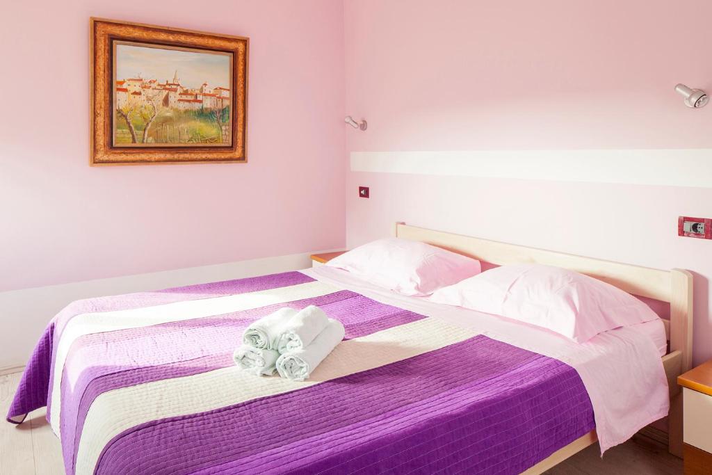 sypialnia z fioletowym łóżkiem i ręcznikami w obiekcie Mon Perin Castrum - Rooms Dado w mieście Bale
