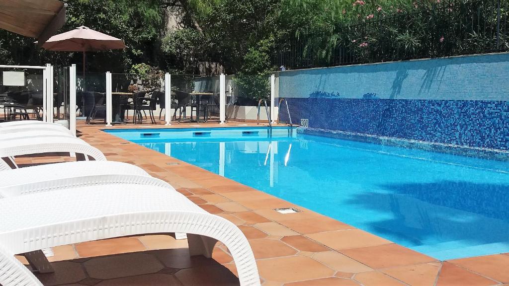 - une piscine avec 2 chaises et un parasol dans l'établissement Amarante Cannes, à Cannes