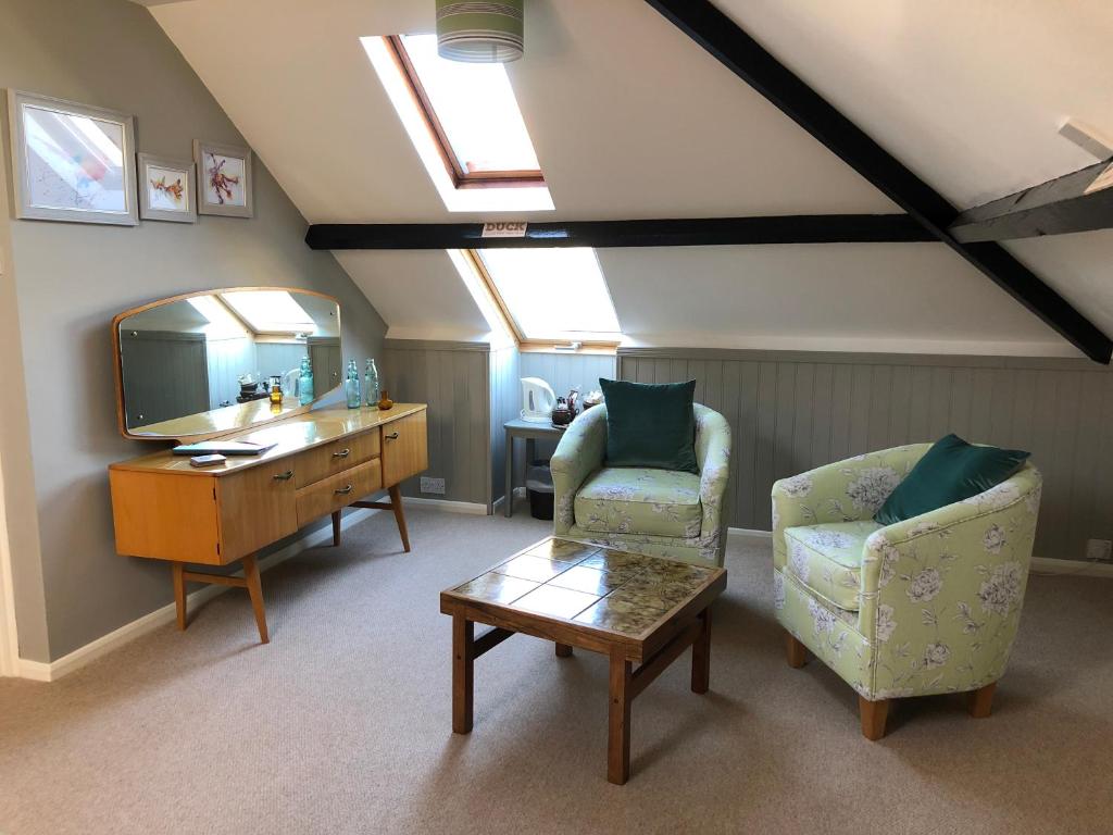 uma sala de estar com 2 cadeiras, uma mesa e um espelho em Burlington House Guest House em Hunstanton