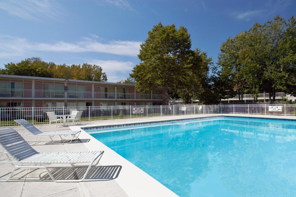 a large swimming pool with chairs and a building at Howard Johnson by Wyndham Albany in Albany