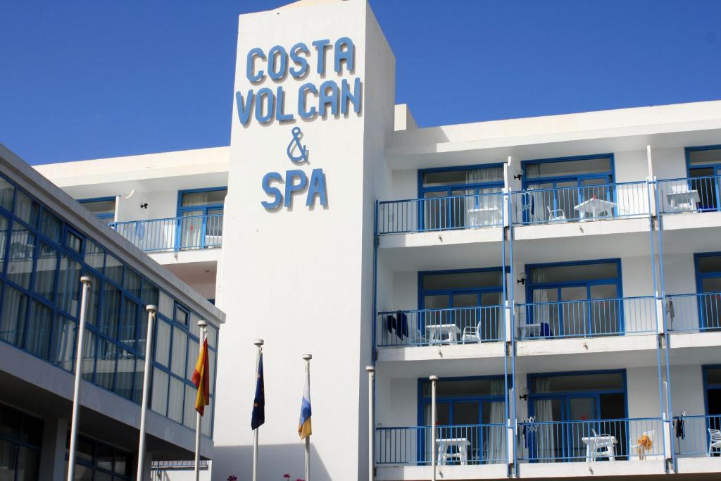 - un bâtiment avec un panneau indiquant costa wolfgan et spa dans l'établissement Aparthotel Costa Volcán & Spa, à Puerto del Carmen