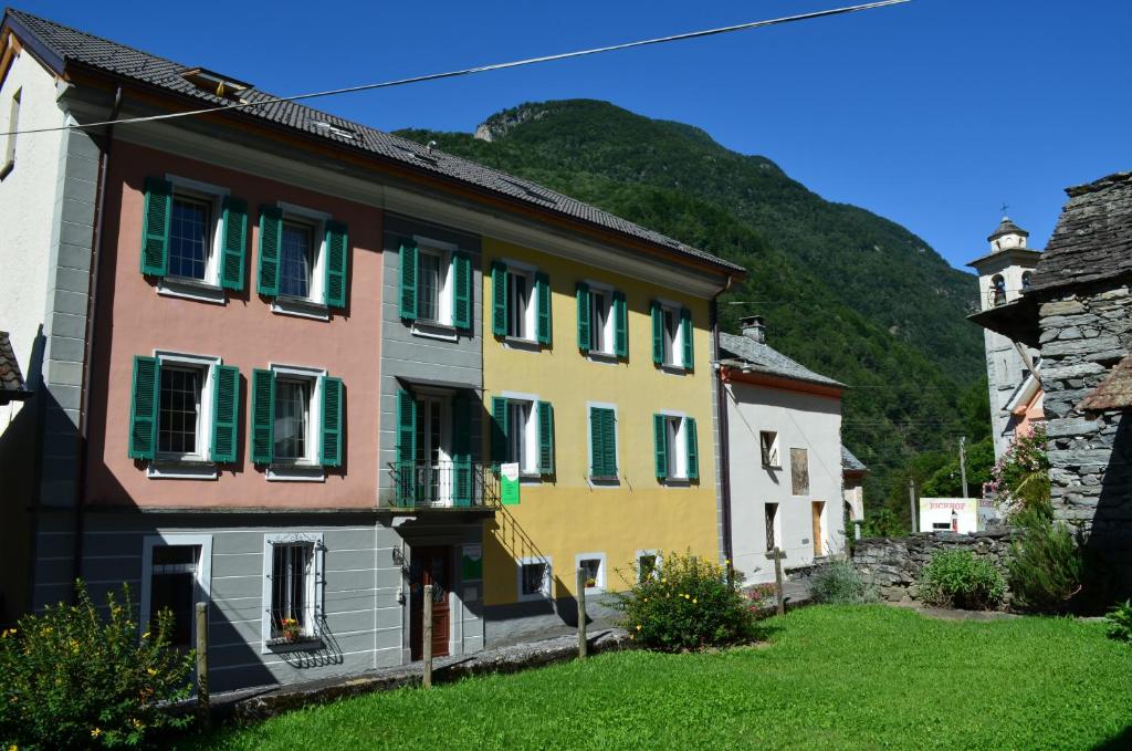 a group of houses with green shutters and a mountain at Hotel Garni Maggia in Coglio