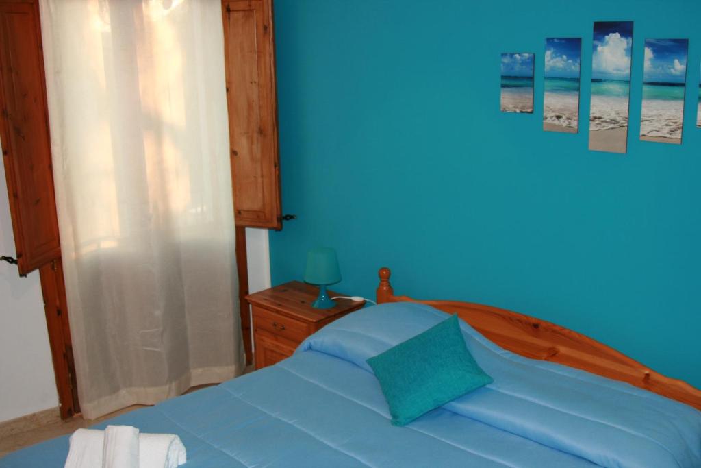 una camera con letto blu e testata in legno di Casa Vacanze Il Cortile a Custonaci