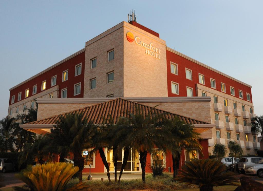 a hotel with palm trees in front of it at Comfort Hotel Araraquara in Araraquara