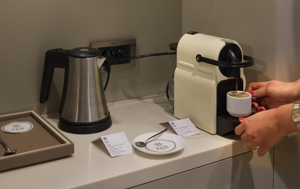 a person holding a cup of coffee in front of a coffee maker at Fer Hotel in Istanbul