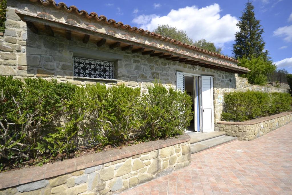 a stone house with a white door and some bushes at Appartamento Valentina in Cortona