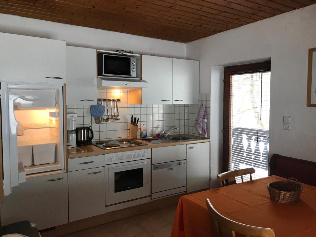 a kitchen with white cabinets and a table and a microwave at Appartement Schmittenweg in Zell am See