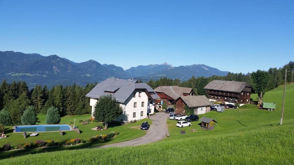 a house on a green hill with mountains in the background at Pension Barzaunerhof in Fresach