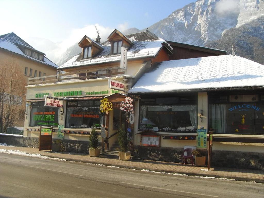 un bâtiment sur le côté d'une rue enneigée dans l'établissement Hotel Le Terminus, au Bourg-dʼOisans