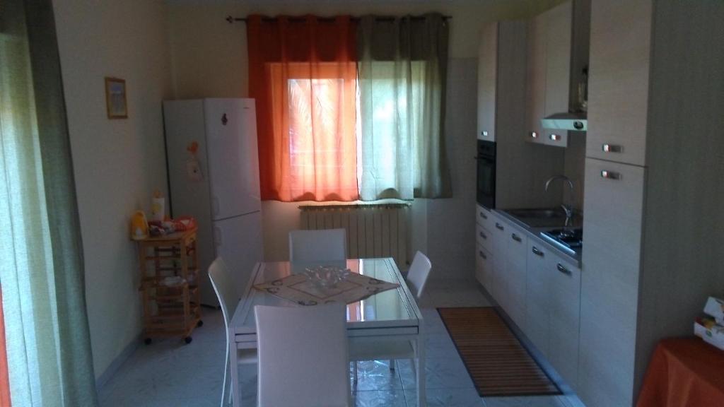 a small kitchen with a table and a refrigerator at Il Noccioleto in Linguaglossa