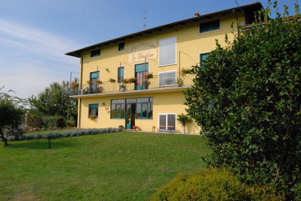 un bâtiment jaune avec une cour devant lui dans l'établissement Agriturismo La Biandrina, à Carpignano Sesia