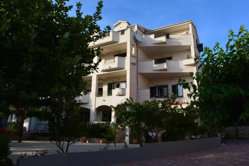 a white building with trees in front of it at Apartments Villa Lili in Tučepi