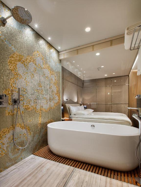 a bathroom with a bath tub and a bedroom at Fer Hotel in Istanbul