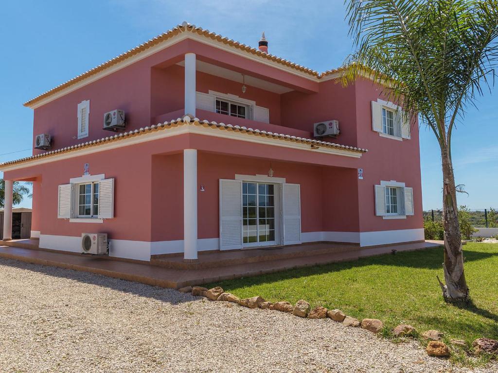 a pink house with a palm tree in front of it at Villa Casa das Amendoeiras by Interhome in Estevais