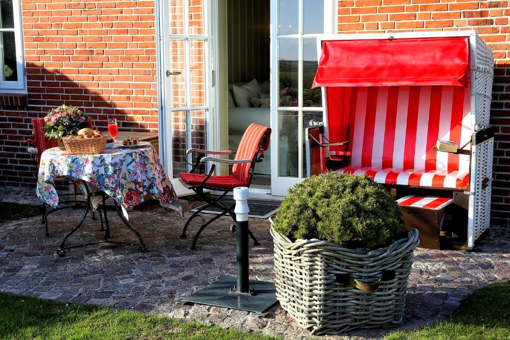 eine Terrasse mit einem Tisch und Stühlen sowie einer roten Decke in der Unterkunft Ferienwohnung Liiger Wal in Morsum