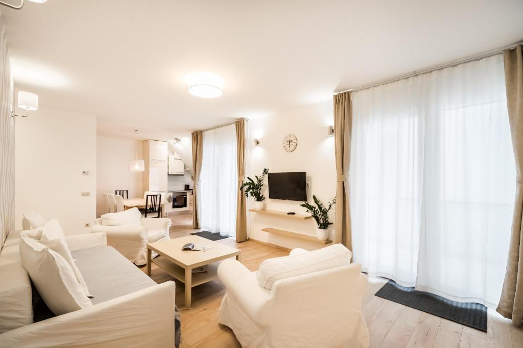 a living room with white furniture and a tv at The Lion's Loft Apartment - 4BR & 3BA - Terrace - AC in Budapest