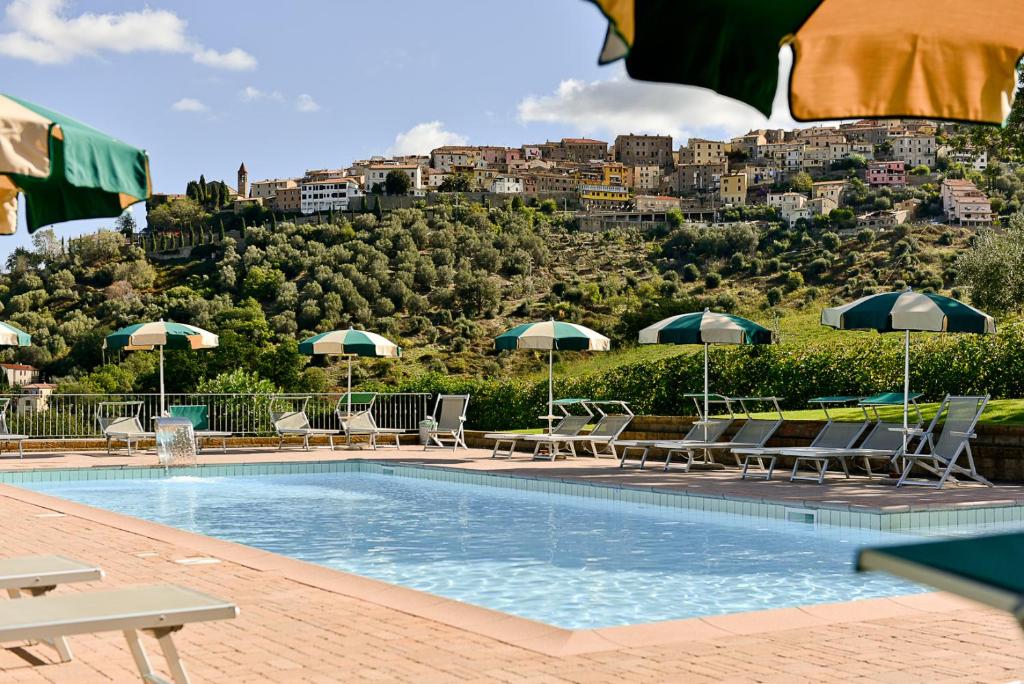 a pool with chairs and umbrellas in front of a hill at Casa Vacanze Bicchi in Scarlino