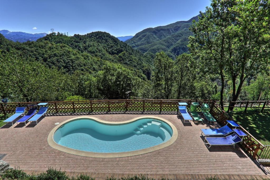 a swimming pool with chairs and mountains in the background at Agriturismo Le Scope in Molazzana