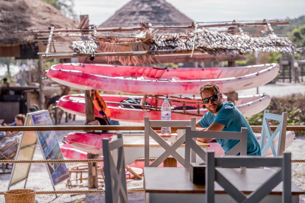 a man sitting at a table in front of boats at Sara Resort in Koh Rong Sanloem