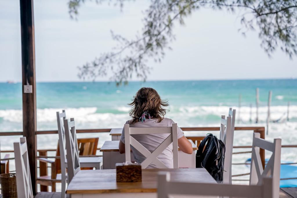 a woman sitting at a table looking out at the ocean at Sara Resort in Koh Rong Sanloem