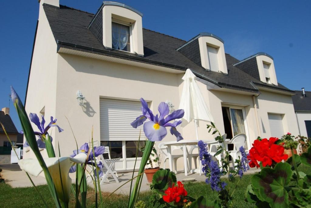 una casa blanca con flores delante en La Roseraie, en Ergué-Gabéric