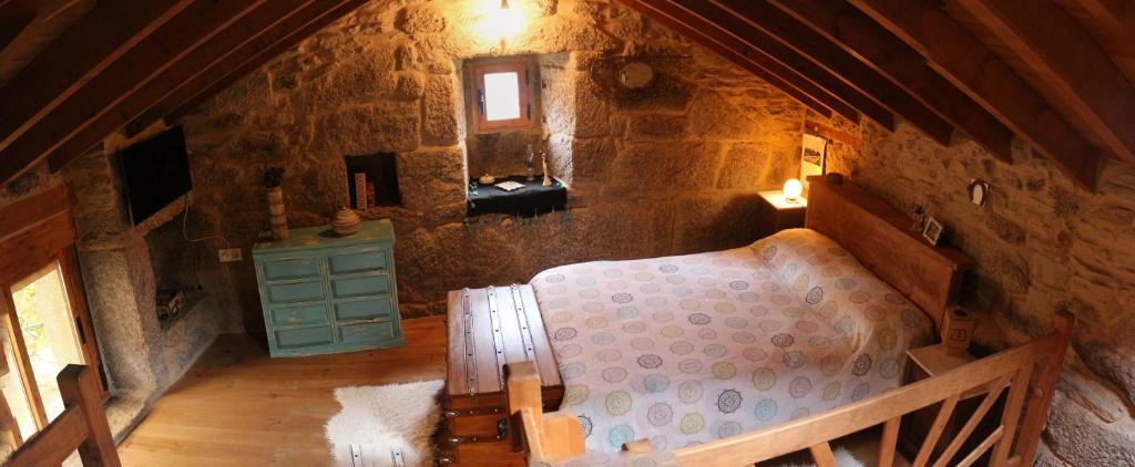 an attic bedroom with a bed in a stone building at Bodega rural tipo loft in Ourense