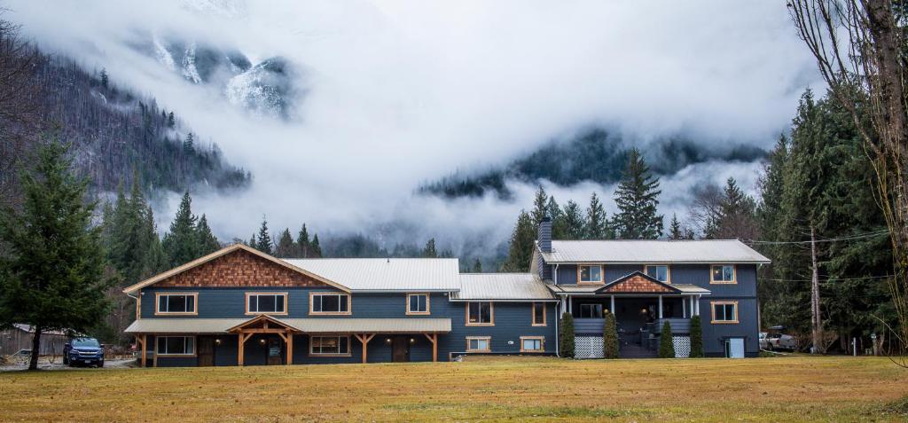 a blue house in a field with a mountain at Bella Coola Eagle Lodge in Bellakula