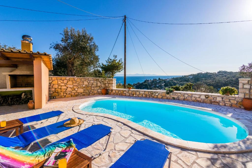 a swimming pool with blue lounge chairs and a villa at Loggos Seaview Cottage with Pool by Konnect in Longós