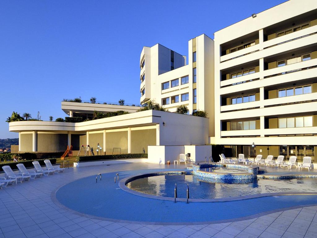 un bâtiment avec une piscine en face d'un bâtiment dans l'établissement Park Hotel Mirabeau, à Montepaone
