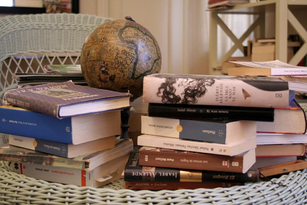a stack of books on a table with a globe at Hostal Rural Luna y Hostal Rural Lunaposada in Candeleda