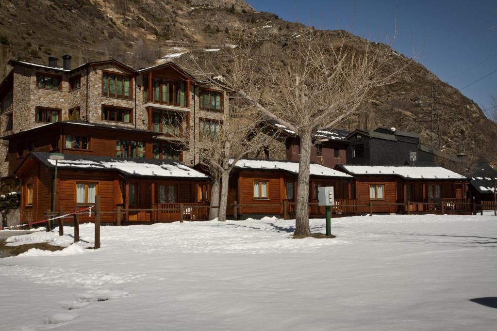 a large wooden building with snow on the ground at Camping - Bungalows Janramon in Canillo