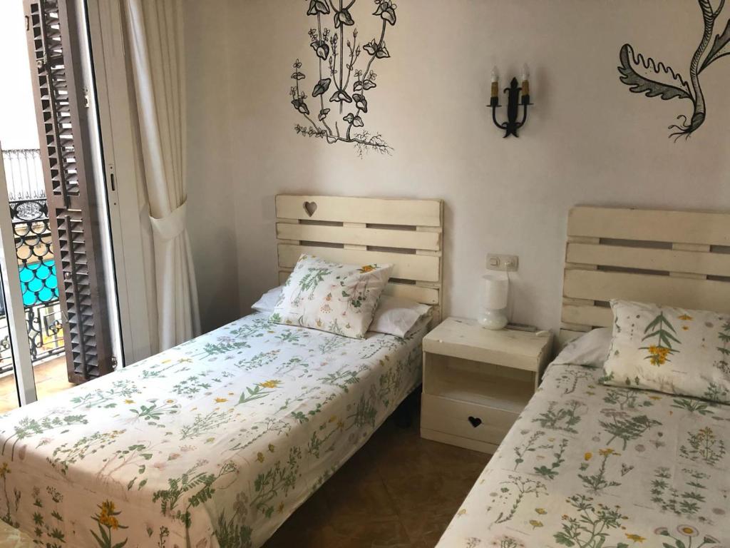 1 dormitorio con 2 camas y ventana en Hostal Parellades, en Sitges