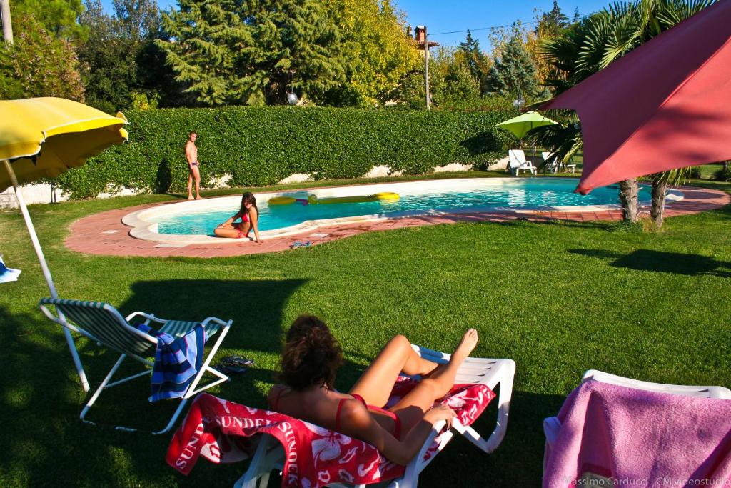 two women laying in lawn chairs by a pool at Agriturismo San Vito in Crocemaroggia