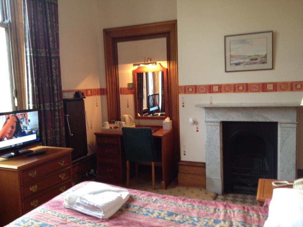 a room with a bed and a desk and a fireplace at Purbeck House Hotel & Louisa Lodge in Swanage
