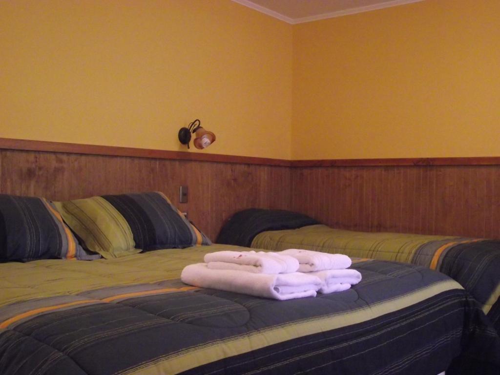 two beds in a room with towels on the bed at Hostal Y Cabañas Don Juan in Villarrica