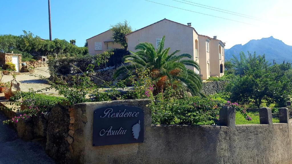a sign on a stone wall in front of a house at Résidence Assuliu in Propriano