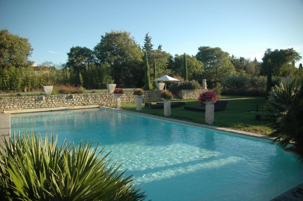 a swimming pool in a yard with a stone wall at Mas des Carassins in Saint-Rémy-de-Provence