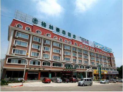 un gran edificio rojo con coches estacionados frente a él en GreenTree Inn Rizhao West Station Suning Plaza, en Rizhao