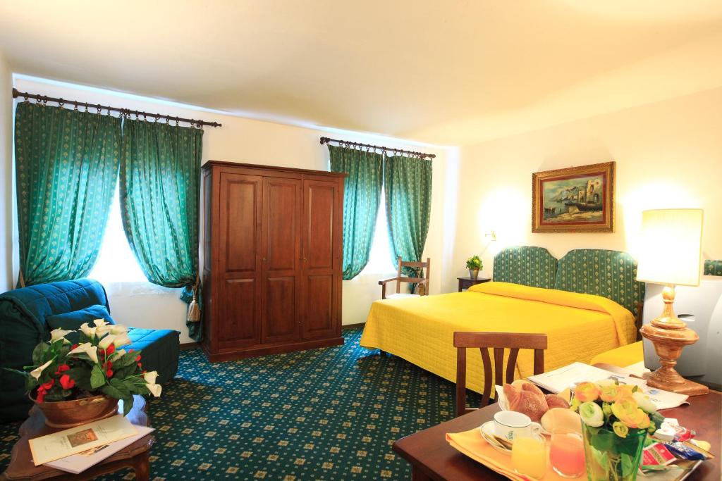 フィレンツェにあるホテル サン ジョルジョ  ＆ オリンピクの黄色のベッドとソファが備わるホテルルームです。