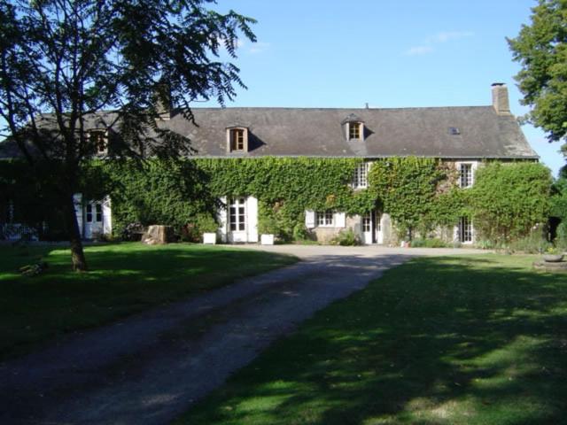 une grande maison avec du lierre sur son côté dans l'établissement Manoir de Pommery, à Sixt-sur-Aff