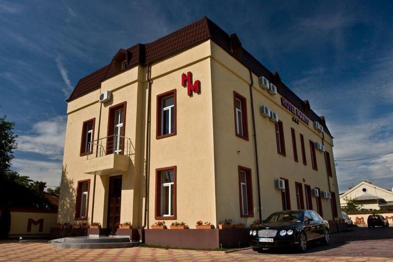 un bâtiment avec une voiture garée devant lui dans l'établissement Hotel Maryo, à Ploieşti