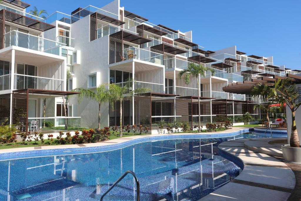an exterior view of a building with a swimming pool at Terrazas Apartments by Bahia Principe in Tulum