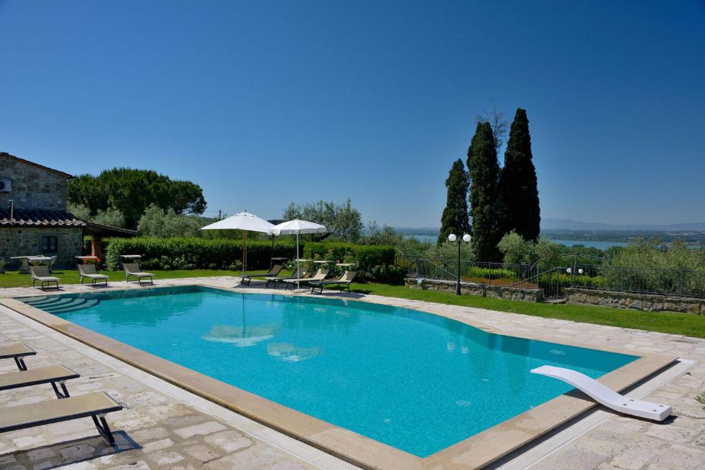 a large swimming pool with chairs and umbrellas at Villa Giulia in Tuoro sul Trasimeno