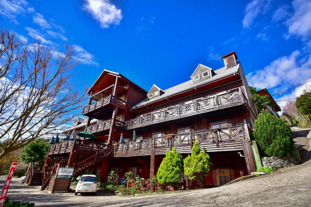 a large wooden building with a car parked in front of it at Beverly B&amp;B in Ren&#39;ai