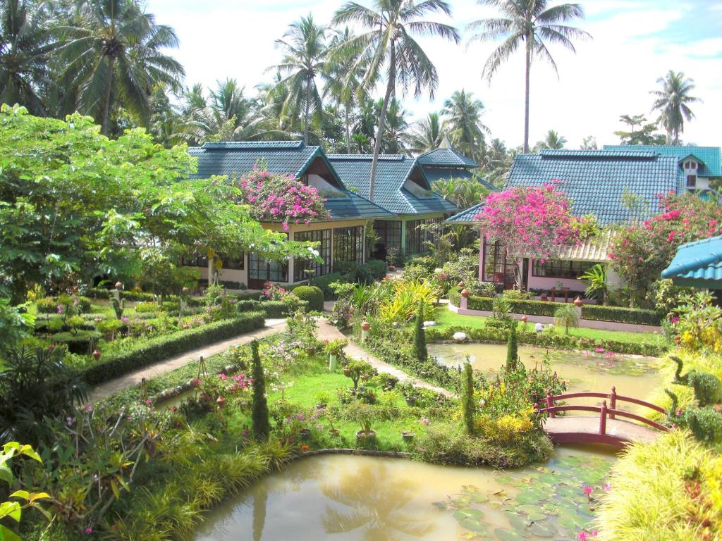 un jardin en face d'une maison avec un étang dans l'établissement Ekman Garden Resort, à Sichon