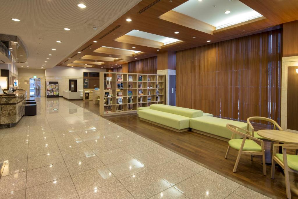 a library with green furniture and a table and chairs at Chisun Grand Nagano in Nagano